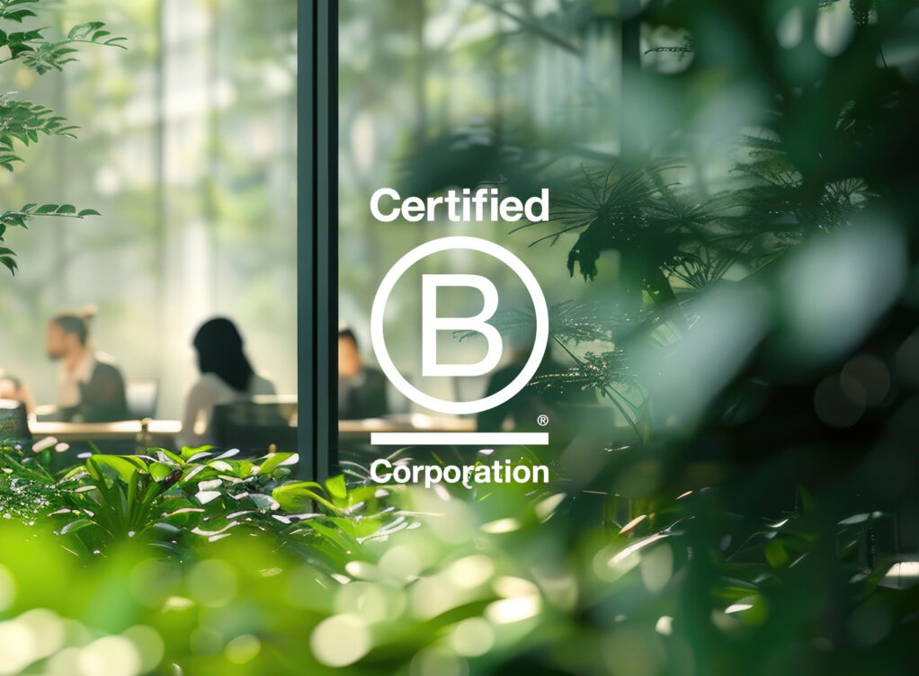 Modern office with lush greenery. B Corp logo overlaid.